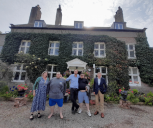 director of operations, Harriet Michael-Phillips, Ben, Tim and Moz with MP David Jones stood outside a beautiful country house with ivy over the walls and a pebble pathway