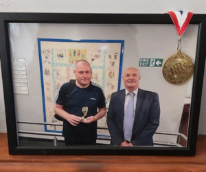 James accepts a medal from his day centre for all the great work he has been doing - the photo is in a frame in their living room with the medal draped over it