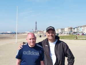 James and Adrian stand in front of Blackpool tower and smile at the camera