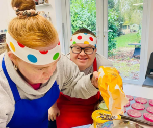 Shared Lives is a bit like fostering adults. Victoria is in the picture - she's weighing out sugar for her next baking project.