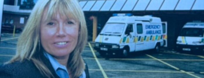 Janet is pictured smiling at the camera. She's blonde ad wearing a blazer and shirt - she's stood in front of an A&E unit, which is where a lot of her work as a police officer took her. Now, she's a Shared Lives carer.